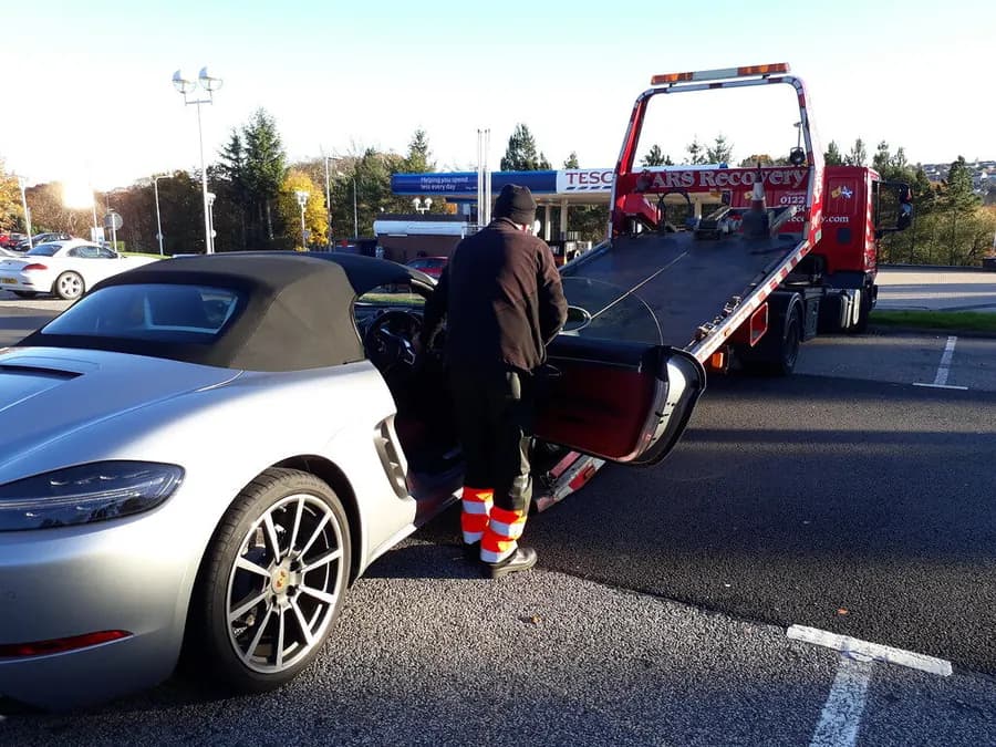 A sports car being loaded onto a recovery truck