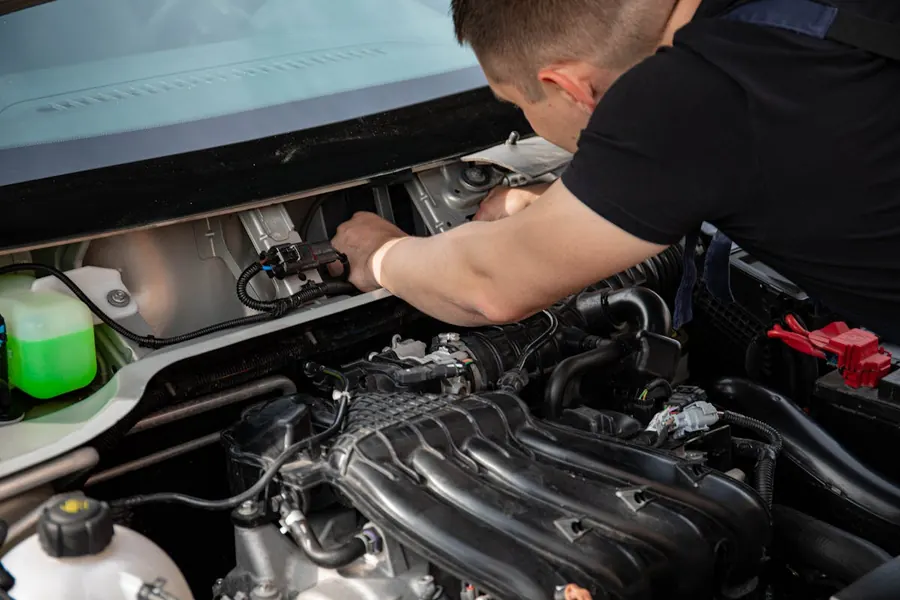 A mechanic with a clipboard checking an open engine bay