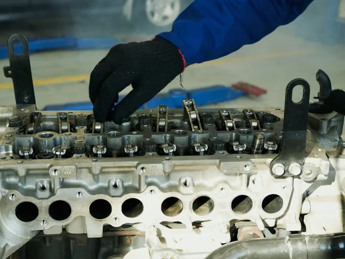 A gloved hand working on an engine’s cylinder head