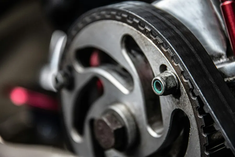 Focused shot of a car engine’s metallic timing belt component, essential for maintenance and repair.